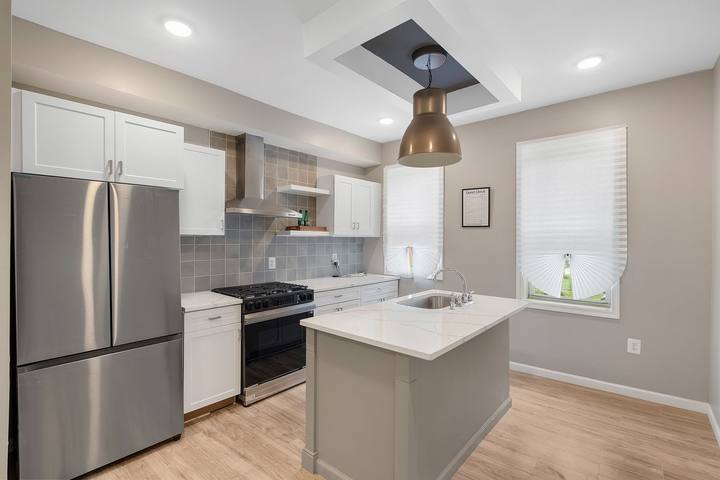 Kitchen island with a stainless steel sink, a stainless refrigerator and the range along the wall