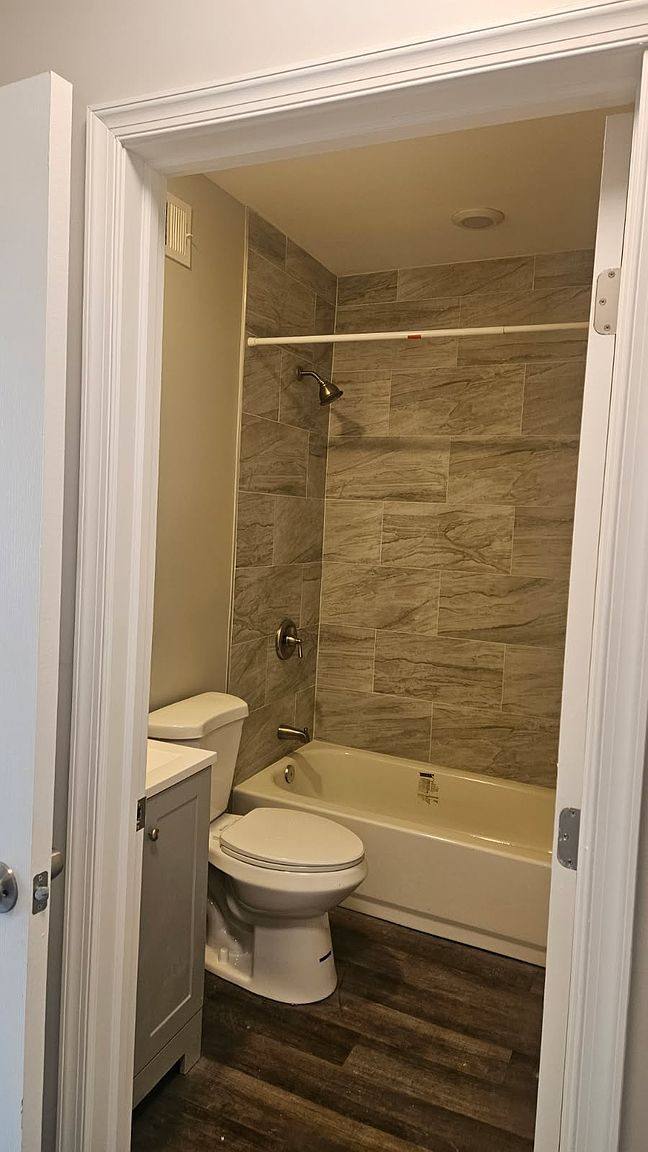 Bathroom with a wood-look tile tub surround and a white toilet