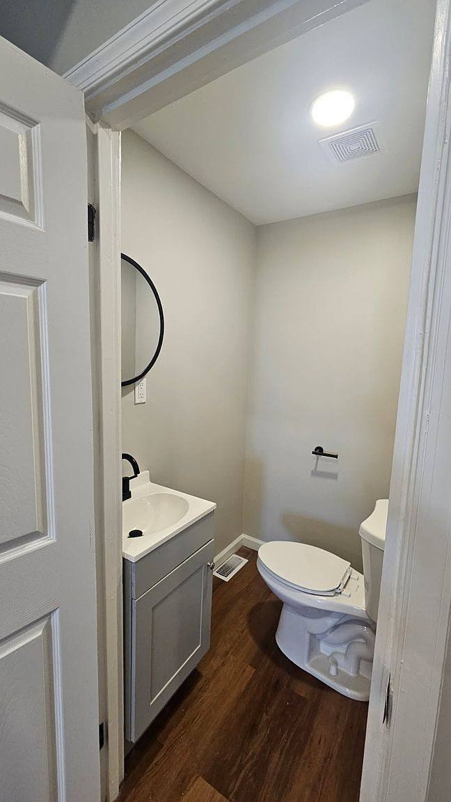 Half bathroom with a white vanity and a round mirror