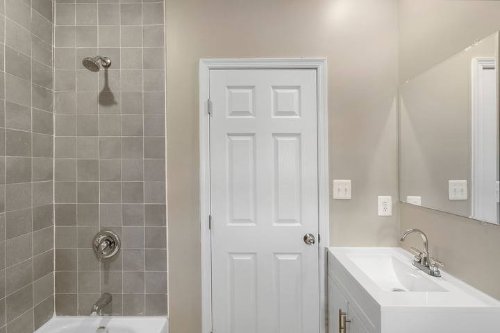 Bathroom with a gray tile tub surround and a white vanity