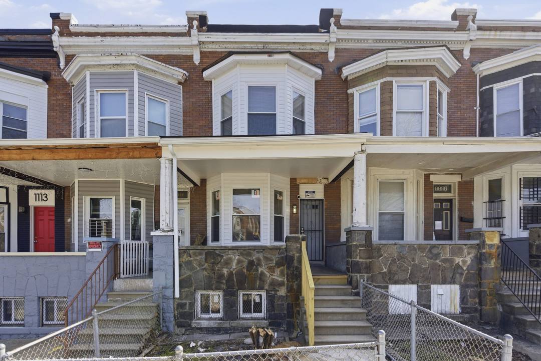 A row of porch-front brick rowhouses in Baltimore