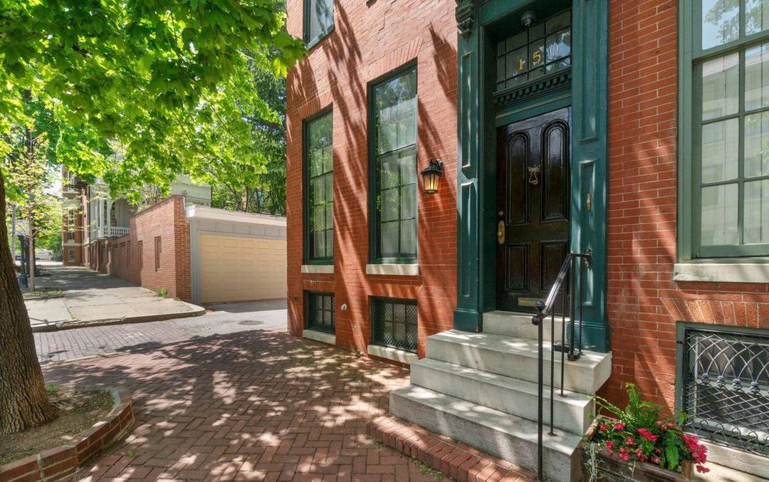 Green front door and stone stoop of a brick Baltimore home