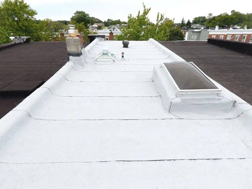 A rowhouse flat roof freshly sealed with white reflective coating